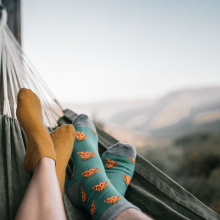 Zwei Personen entspannen mit bunt gemusterten Socken in einer Hängematte mit weitem Blick über die Berge