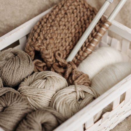 Korb mit Wollknäueln in Naturtönen, Stricknadeln und angefangenem Strickstück – Alpakagarn „Herdenglück“